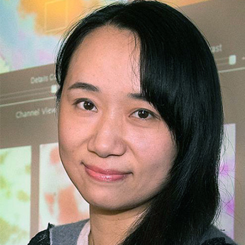 Headshot of Brookhaven researcher Wei (Celia) Xu. She smiles and wears a light gray top. She stands in front of a backdrop of visualizations.