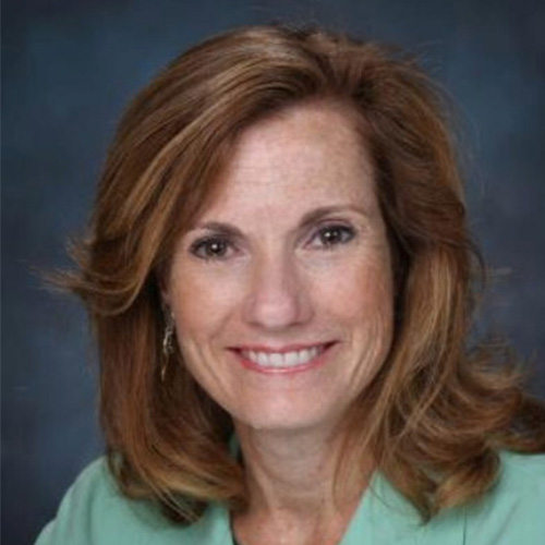 Headshot of Hewlett Packard Enterprise speaker Trish Damkroger. She smiles and wears a spring green button-up. She stands in front of a gray and blue backdrop.